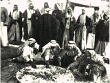 Villagers who have been invited to a feast by a wealthy sheik. Guests eat in relays and the common dish is frequently refilled as the feast progresses. An early photograph.
